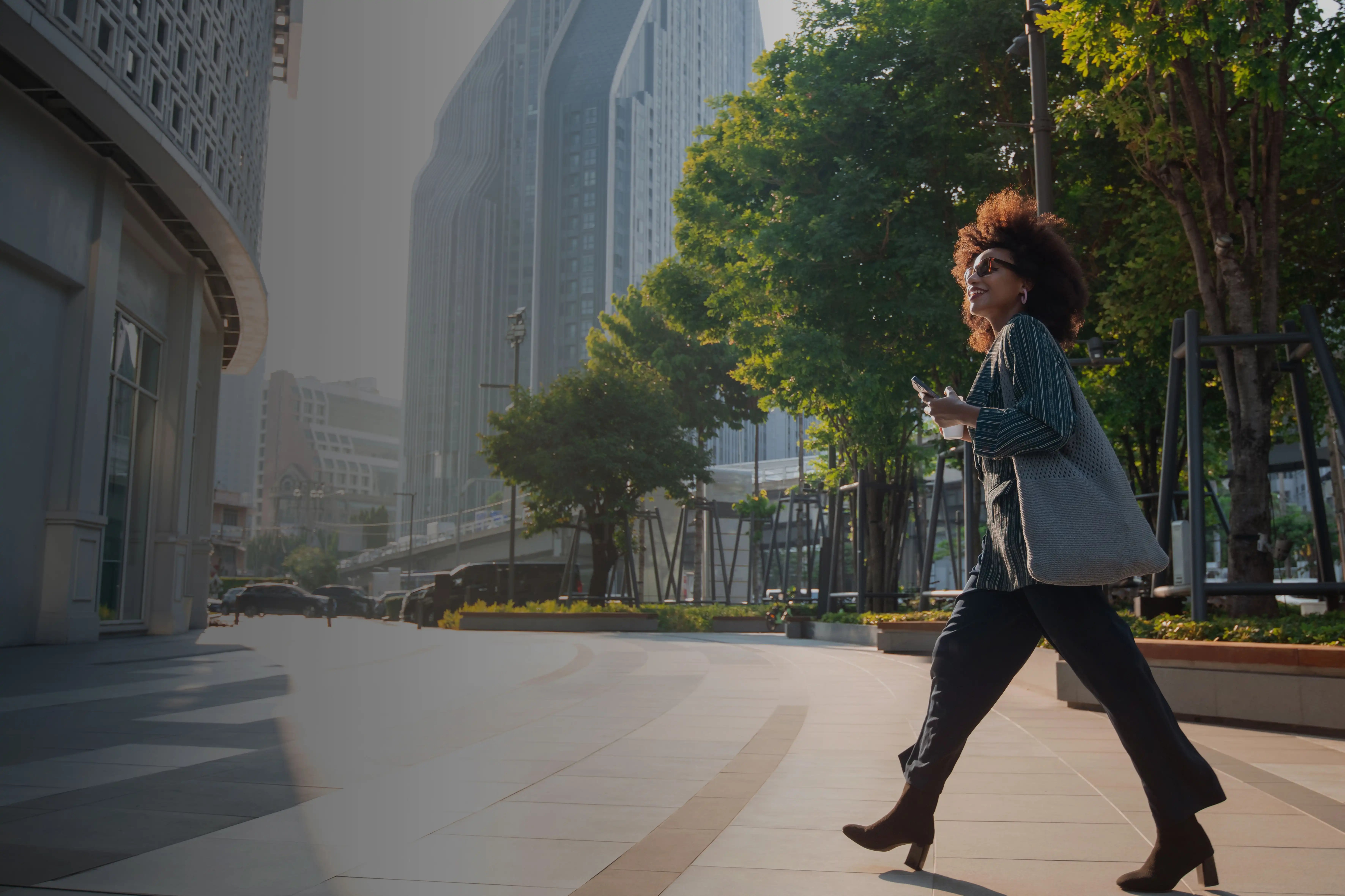 Lady walking across road in a tree lined city street