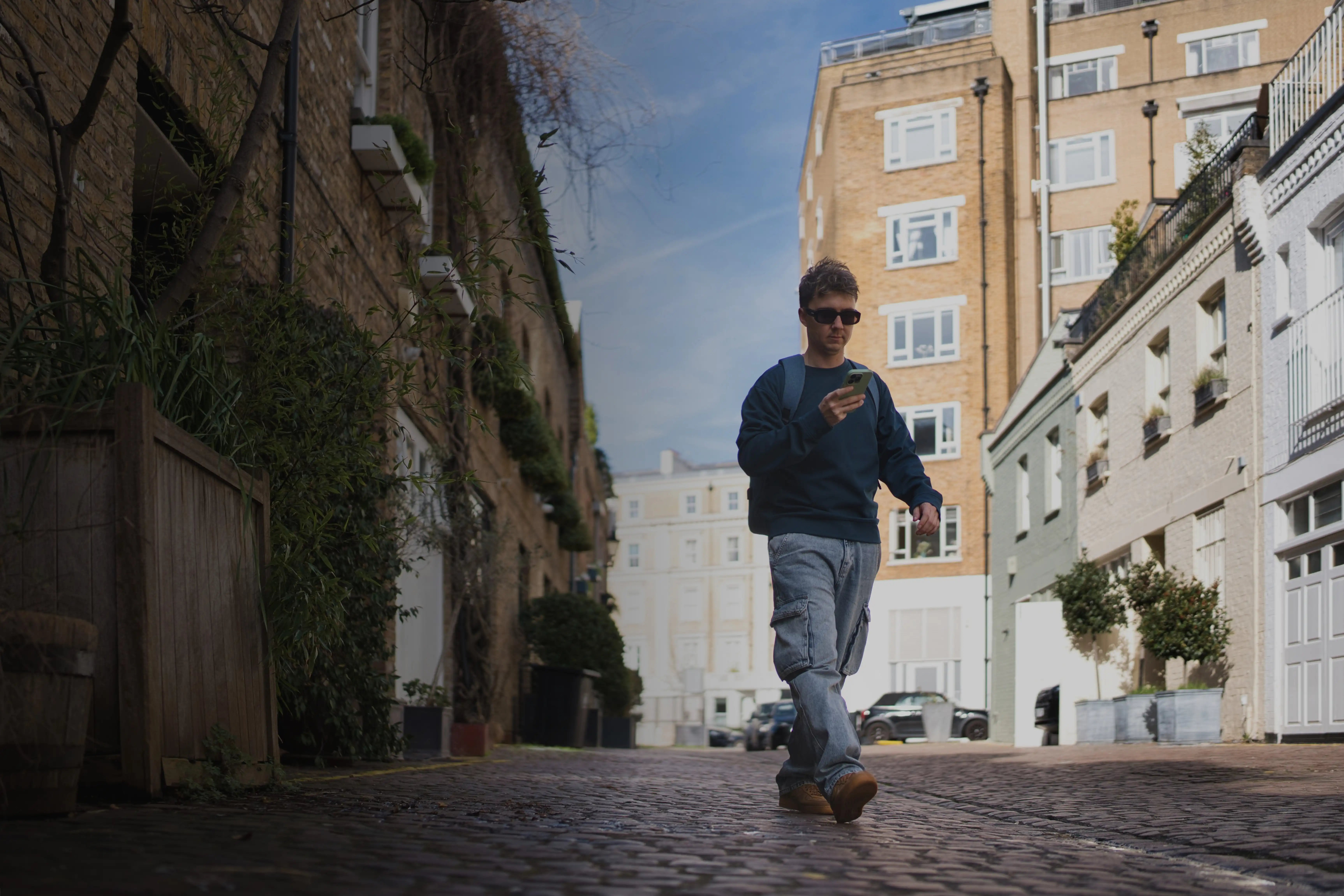young man walking down a city street looking at phone