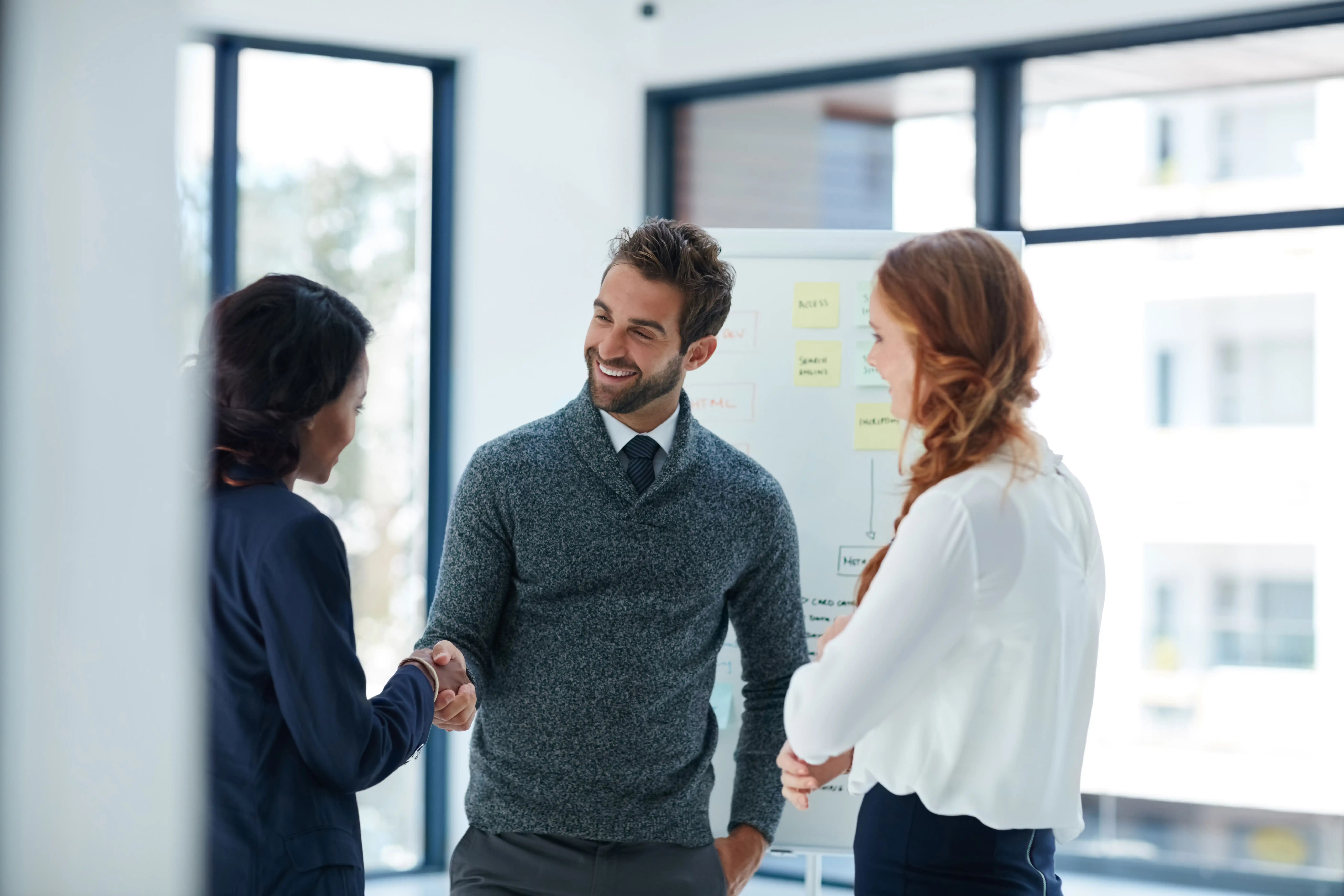 credit risk meeting between three colleagues, shaking hands and smiling