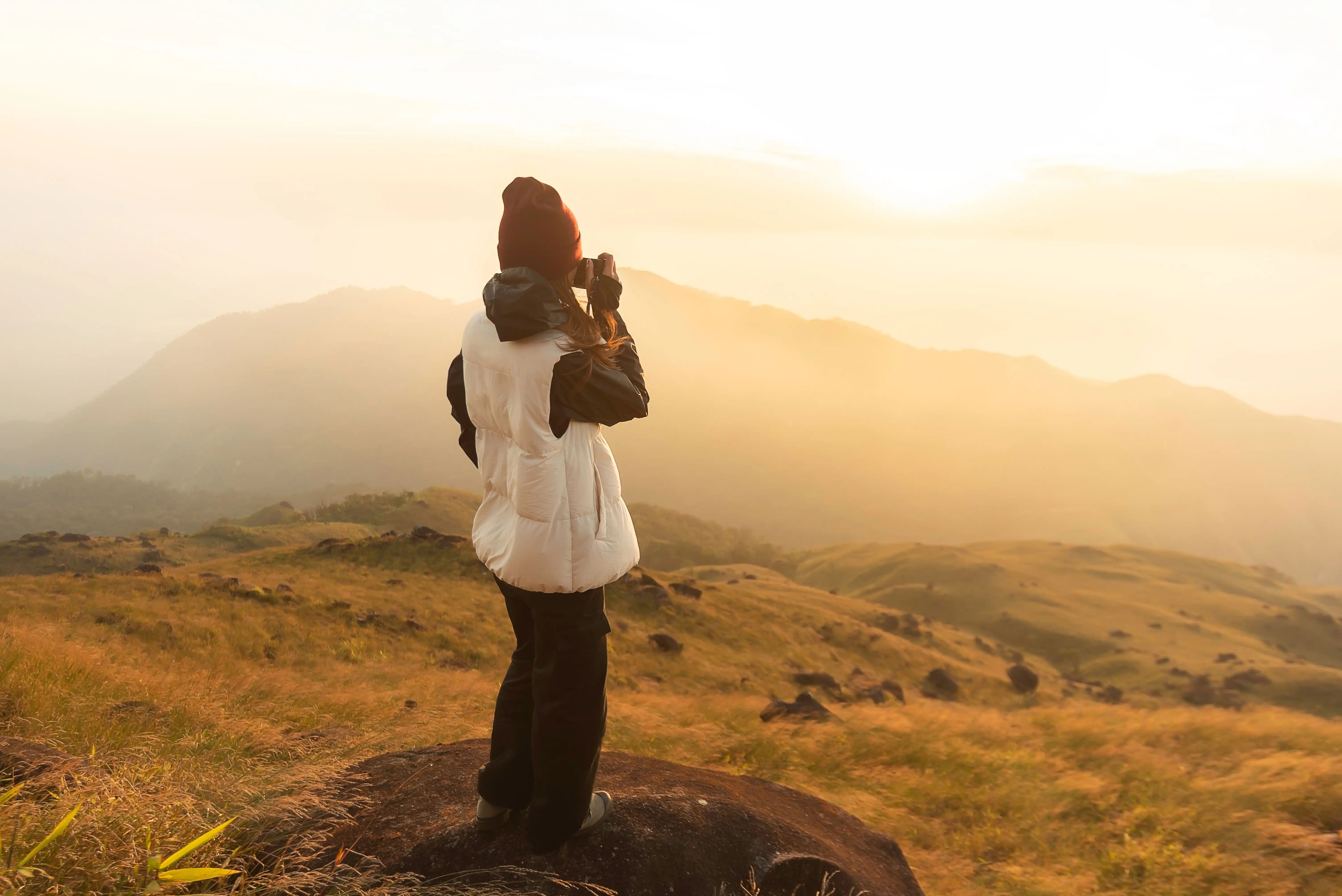 young woman with a beanie hat looking at the spanning beautiful view at sunset